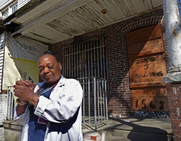 Carlita Smith holds her hands together in prayer in front of a Camden home