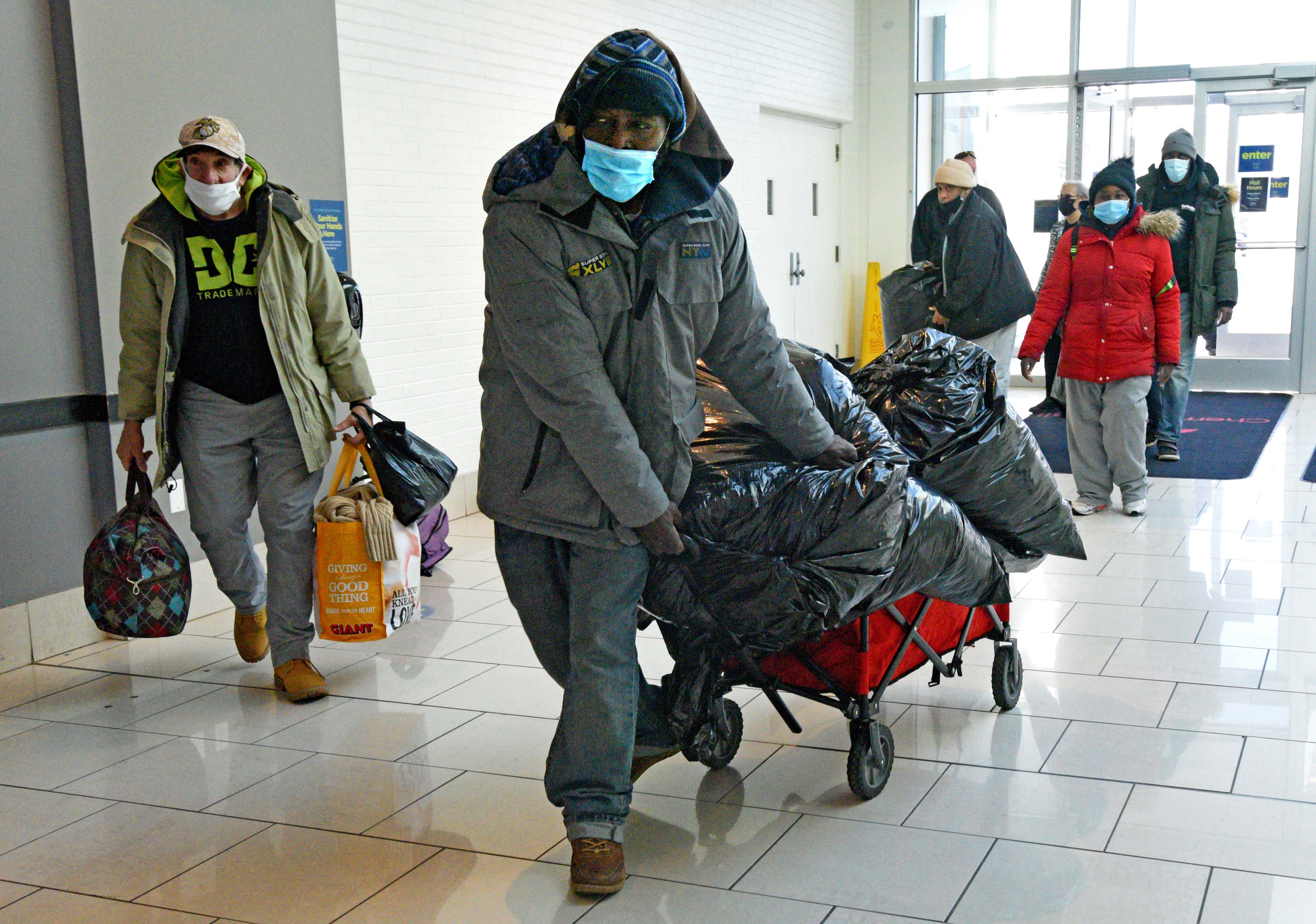 Unhoused individuals, led by Tawanda Jones, bring blankets and their belongings into the Cherry Hill Mall