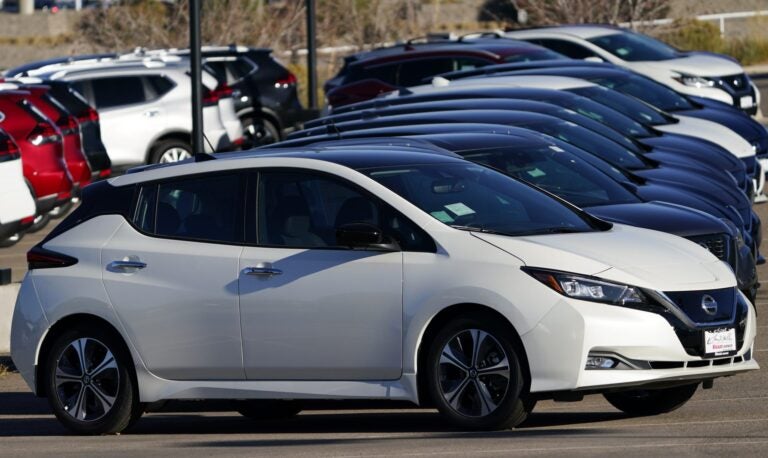 A line of Leaf electric vehicles sits at a Nissan dealership