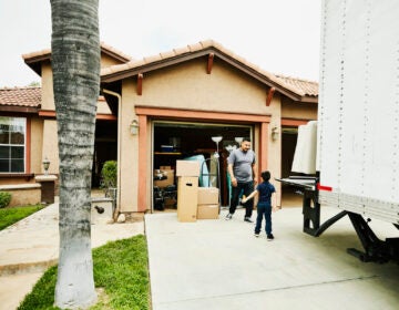 Young son helping father move items from moving truck into new house