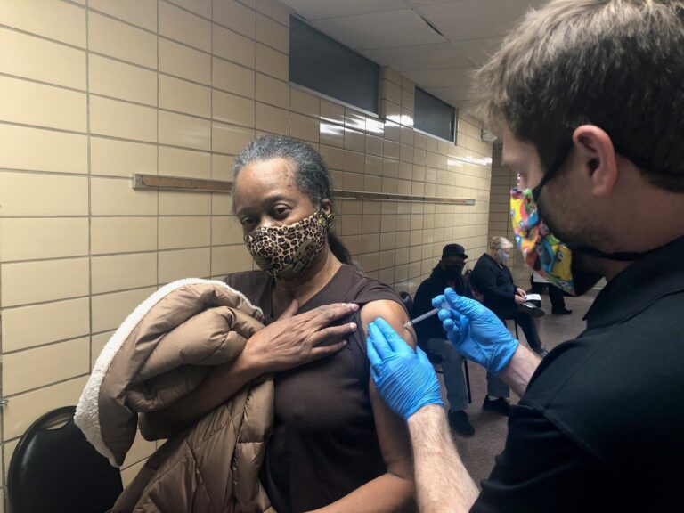 Dr. Rick Pescatore, chief physician at the Delaware Division of Public Health, gives a shot of the Pfizer vaccine to Brenda Jones at the Rose Hill Community Center. (Cris Barrish/WHYY)