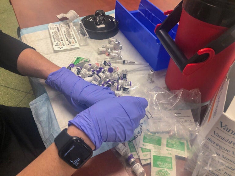 A health worker at a vaccination event in March 2021 at Rose Hill Community Center south of Wilmington organizes doses. (Cris Barrish/WHYY)