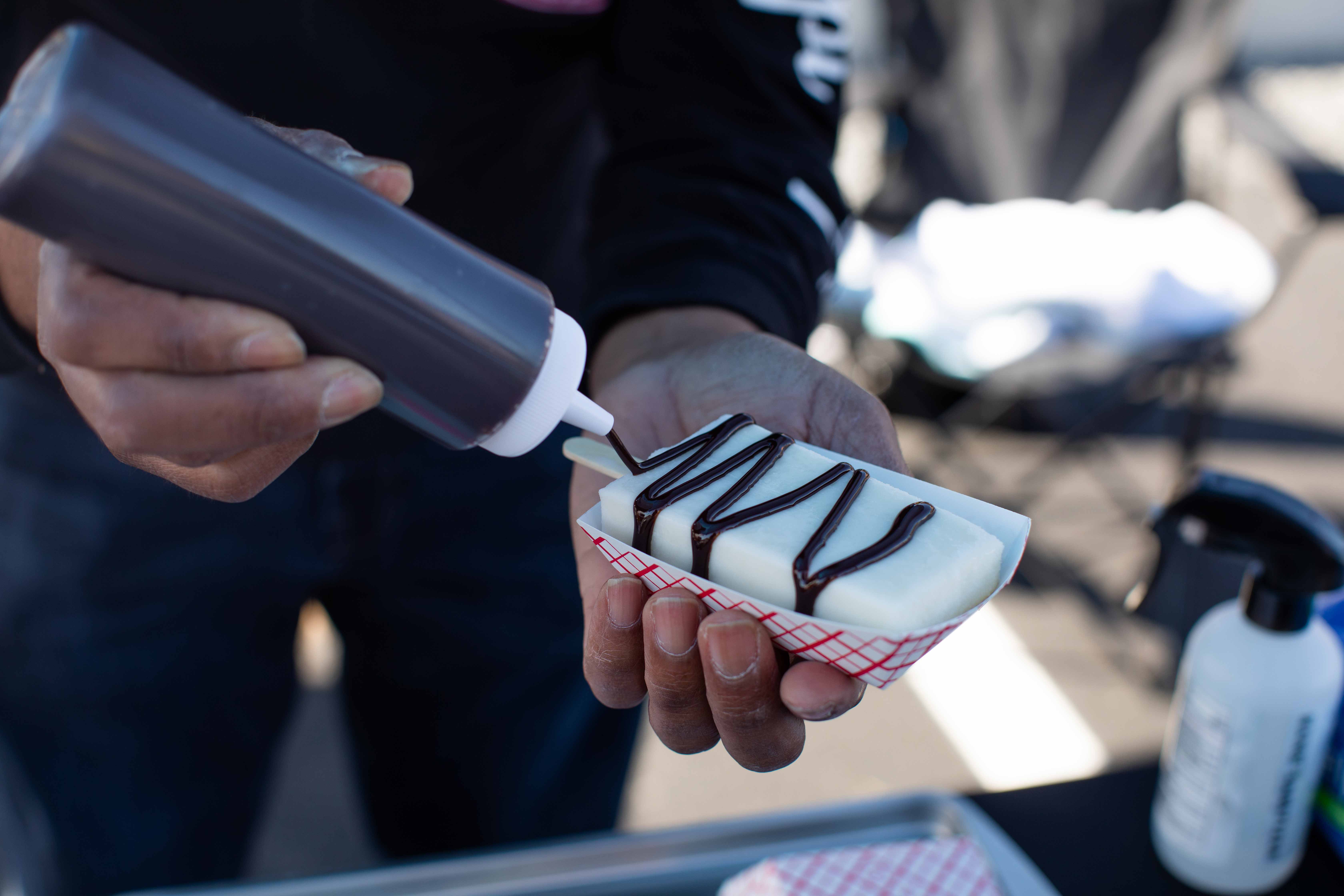 Alexie Encarnación prepares an artisanal paleta with toppings at La Placita. (Becca Haydu for WHYY)