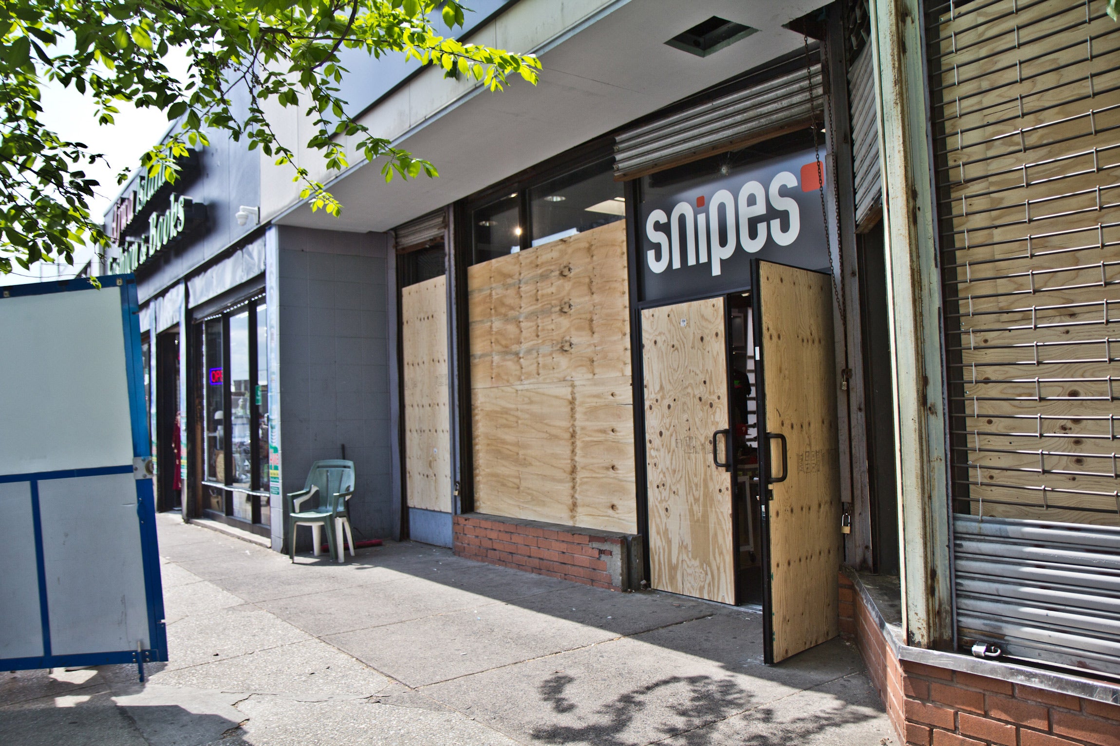 Snipes, Foot Locker and the Puma store on 52nd Street in West Philadelphia remained boarded up the day after the verdict was delivered in the trial of Derek Chauvin on April 21, 2021. (Kimberly Paynter/WHYY)