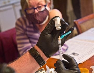 Paramedic Jim McCanns prepares a first dose of the Moderna COVID-19 vaccine for Lucille Breslin at her home in Upper Darby on April 6, 2021. (Kimberly Paynter/WHYY)