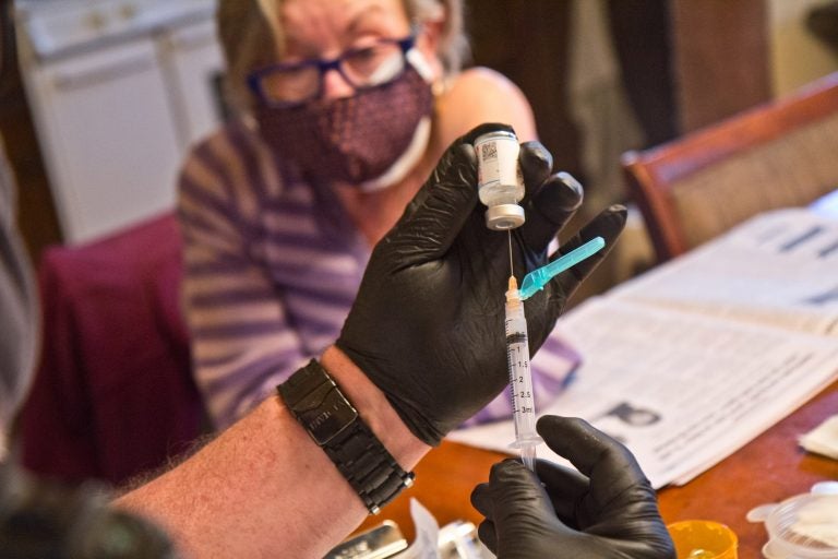 Paramedic Jim McCanns prepares a first dose of the Moderna COVID-19 vaccine for Lucille Breslin at her home in Upper Darby on April 6, 2021. (Kimberly Paynter/WHYY)