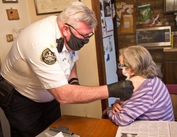 Paramedic Jim McCanns prepares to administer a first dose of the Moderna COVID-19 vaccine to Lucille Breslin at her home in Upper Darby on April 6, 2021. (Kimberly Paynter/WHYY)