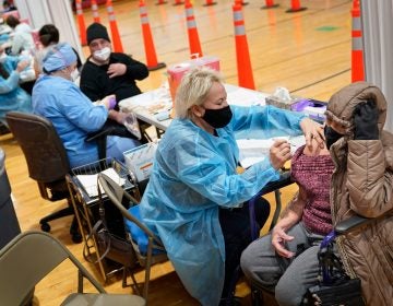 Miriam Palomino, right, receives the COVID-19 vaccine in Paterson