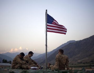 FILE - In this Sept. 11, 2011 file photo, US soldiers sit beneath an American flag just raised to commemorate the tenth anniversary of the 9/11 attacks at Forward Operating Base Bostick in Kunar province. (AP Photo/David Goldman, File)