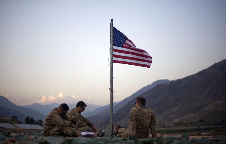 FILE - In this Sept. 11, 2011 file photo, US soldiers sit beneath an American flag just raised to commemorate the tenth anniversary of the 9/11 attacks at Forward Operating Base Bostick in Kunar province. (AP Photo/David Goldman, File)