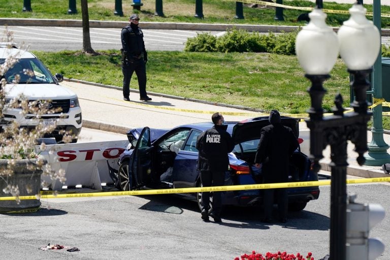 U.S. Capitol Police officers stand near a car that crashed into a barrier on Capitol Hill in Washington, Friday, April 2, 2021. (AP Photo/J. Scott Applewhite)