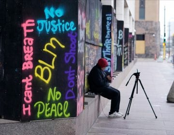 A person videotapes across the street from the Hennepin County Government Center, Thursday, April 8, 2021, in Minneapolis where testimony continues in the trial of former Minneapolis police officer Derek Chauvin. (AP Photo/Jim Mone)