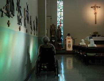 A resident of St. Anne Home sits bathed in sunlight streaming through a stained glass window during morning Mass attended by nuns and residents of the nursing facility in Greensburg, Pa., on Thursday, March 25, 2021. (AP Photo/Jessie Wardarski)