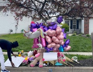 A man adjusts a sign near a memorial at the scene in the Columbus, Ohio neighborhood Friday, April 23, 2021 where 16-year-old Ma'Khia Bryant was fatally shot by police as she swung at two other people with a knife on Tuesday, April 20. (AP Photo/Farnoush Amiri)