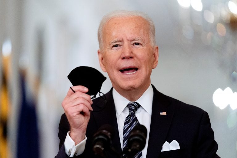 Joe Biden holds up his mask as he speaks about the COVID-19 pandemic