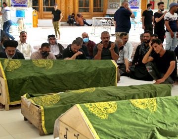 Mourners pray near the coffins of coronavirus patients killed in a hospital fire during their funeral at the Imam Ali shrin