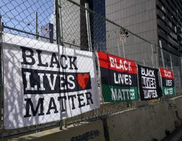 Signs and flags line the fence at the Hennepin County Government Center