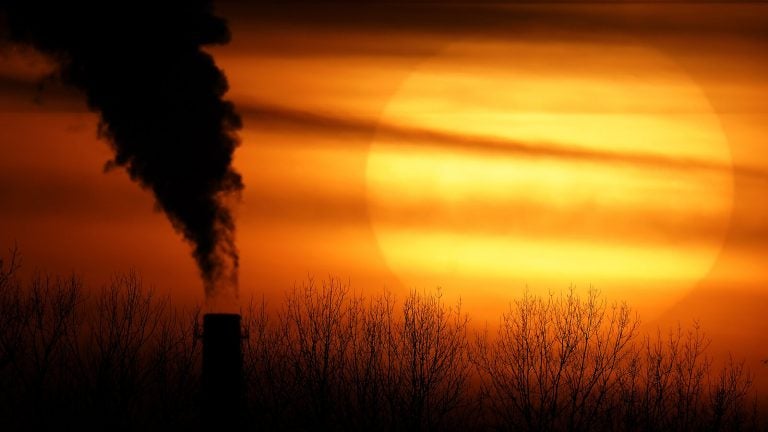 Emissions from a coal-fired power plant are silhouetted against the setting sun