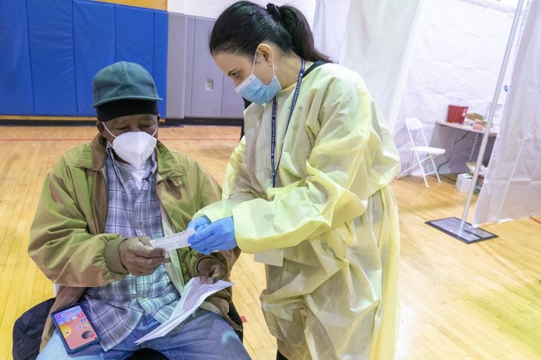 Registered Nurse Rita Alba points out to Beltran Orlando the return date on his vaccination card