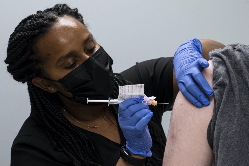 Cole Smith receives a Moderna variant vaccine shot from clinical research nurse Tigisty Girmay