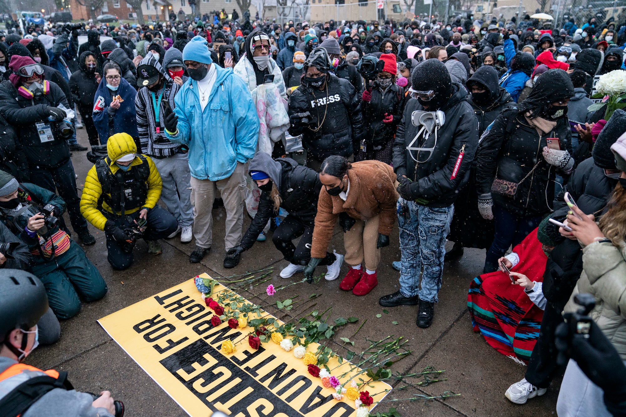 Flowers are placed on a banner as demonstrators gather outside the Brooklyn Center Police Department