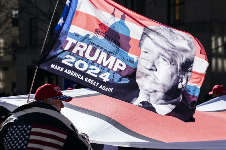 A Trump supporter carries a flag that says 