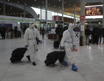 Passengers wearing protective gear arrive to board their plane