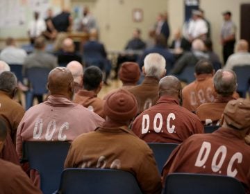 People who are incarcerated in a Pennsylvania prison sit inside while wearing DOC uniforms