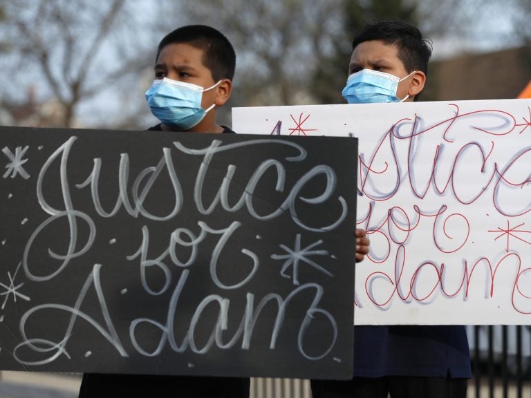 Two boys hold signs at an April 6 news conference, days after a Chicago police officer fatally shot 13-year-old Adam Toledo. (Shafkat Anowar/AP Photo)