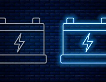 Glowing neon line Car battery icon isolated on brick wall background