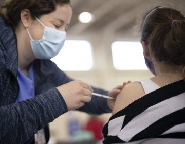 A member of Penn State Health's vaccination clinic staff administers a dose of the COVID-19 vaccine.