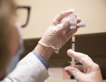 A pharmacist fills a syringe with COVID-19 vaccine