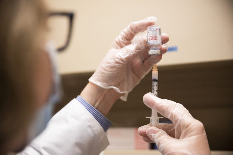 A pharmacist fills a syringe with COVID-19 vaccine