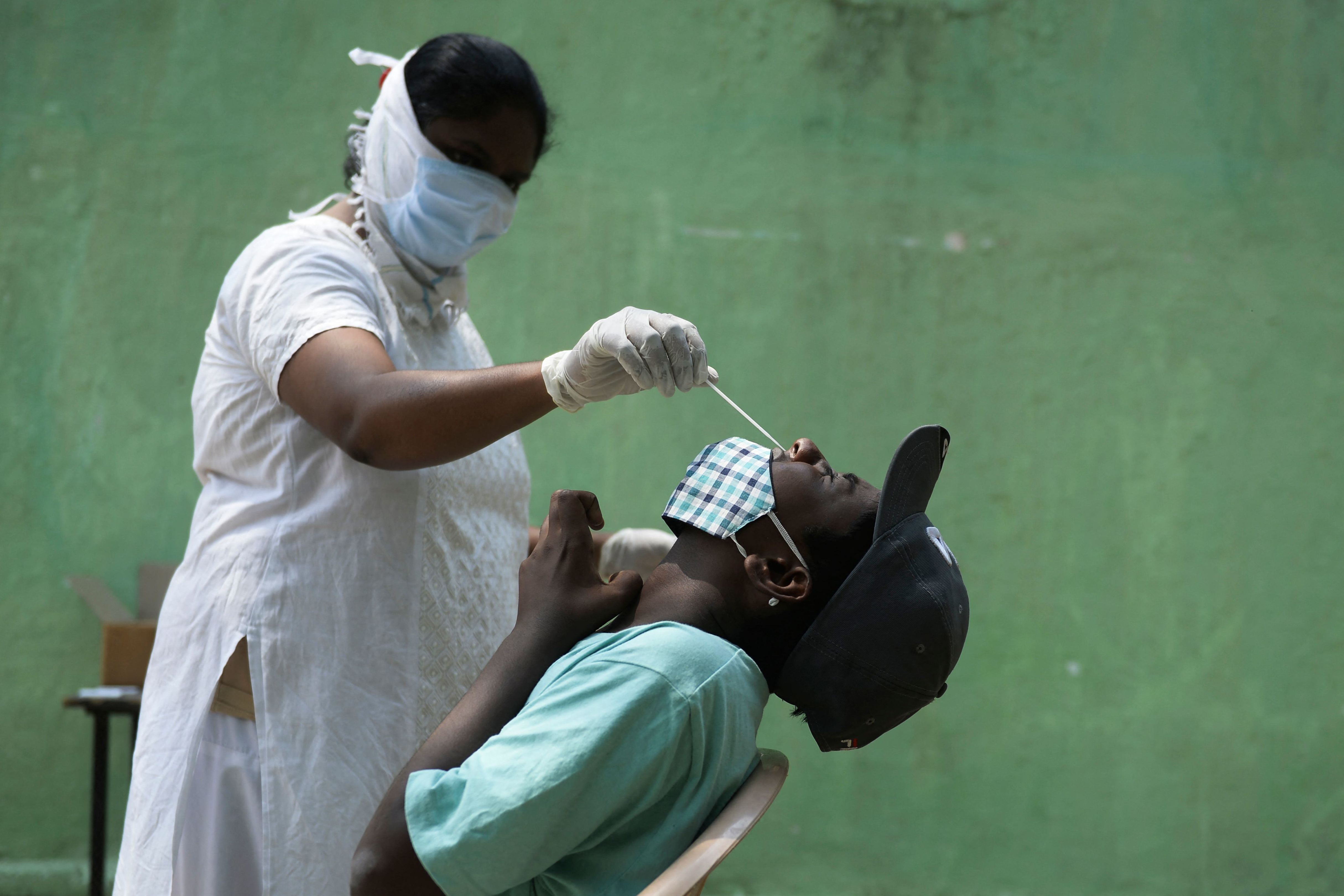 A health worker collects a nasal swab sample from a man to test for COVID-19