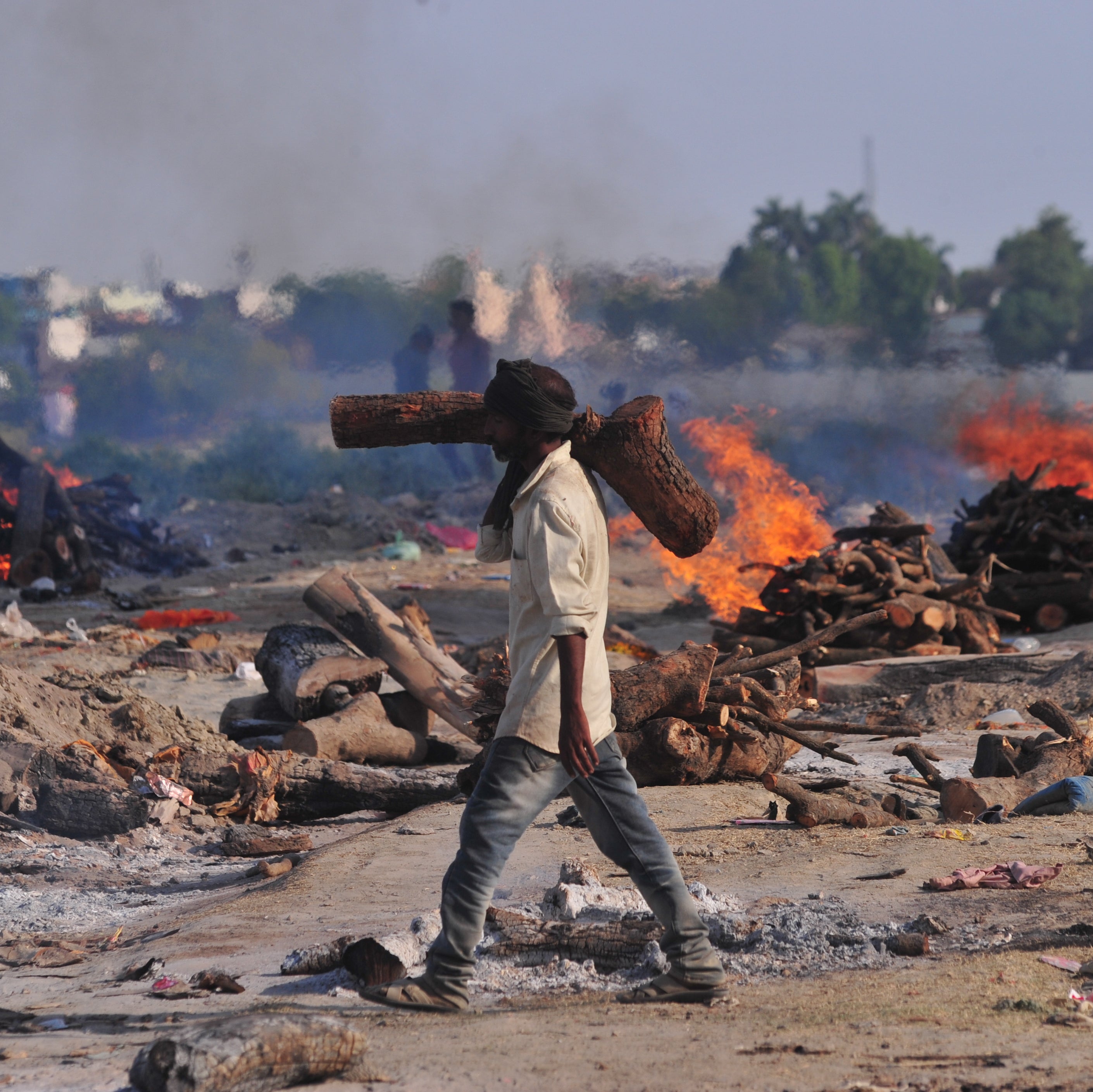 A worker carries wood to a mass cremation site on the banks of the Ganges River in Allahabad