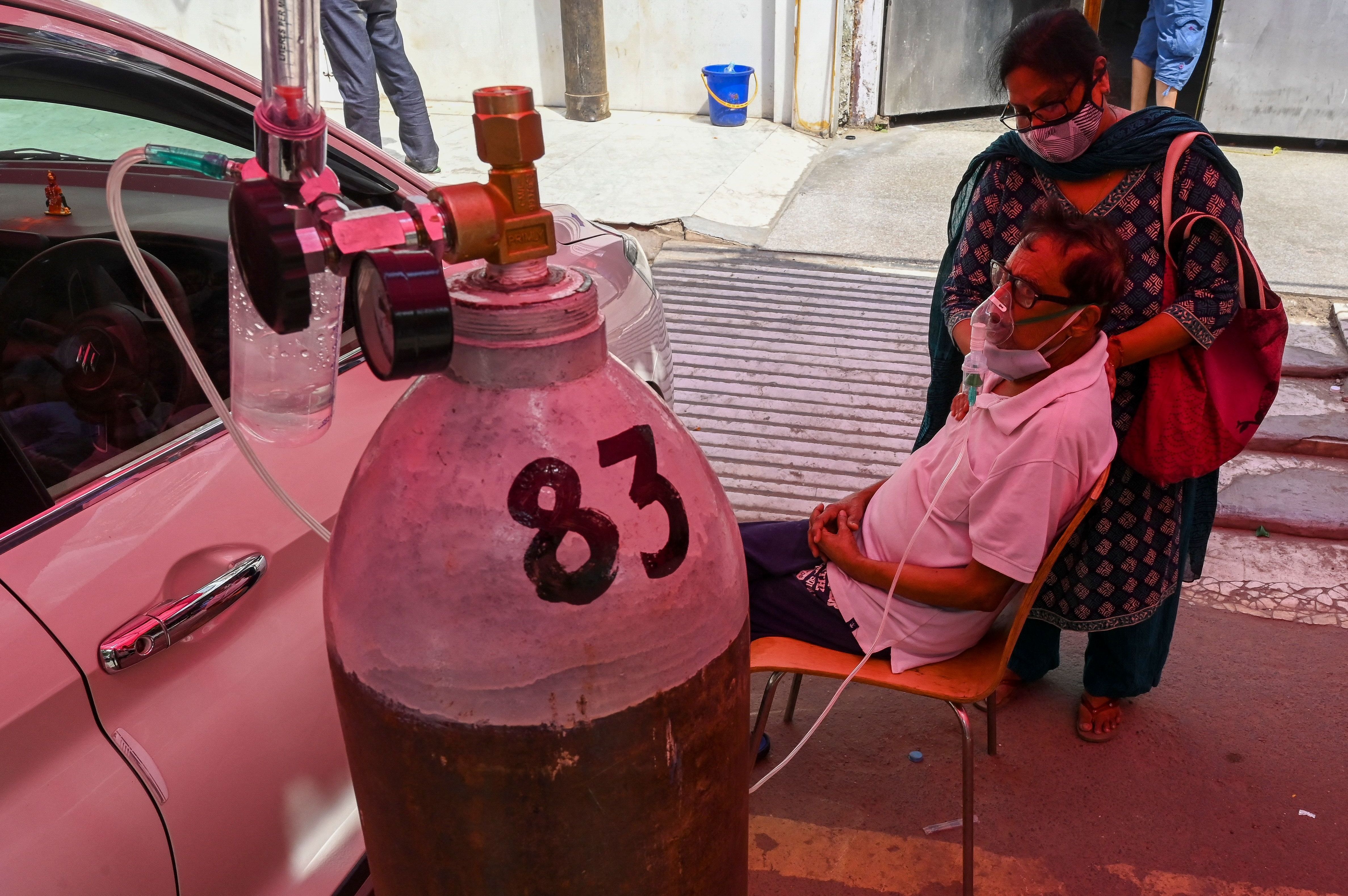 A COVID-19 patient breathes with the help of oxygen at a tent installed along a roadside