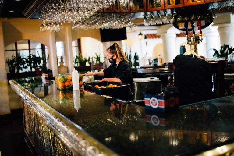 A bartender works while wearing a face mask