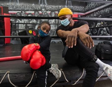 8 year-old Lewis King hangs with Maleek Jackson at his boxing gym in Northern Liberties. (Kimberly Paynter/WHYY)