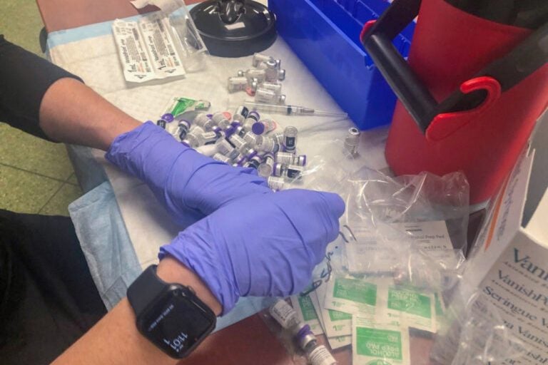 A worker organizes vaccine doses during a recent event at Rose Hill Community Center near New Castle. (Cris Barrish/WHYY)