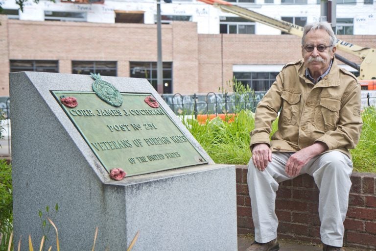 Joel Spivak sits next to a WWI memorial