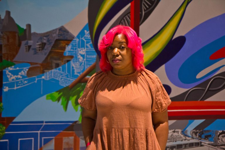 Artist Serena Saunders with her mural 'The Path' at the Bulletin Building across from 30th Street Station in Philadelphia. (Kimberly Paynter/WHYY)