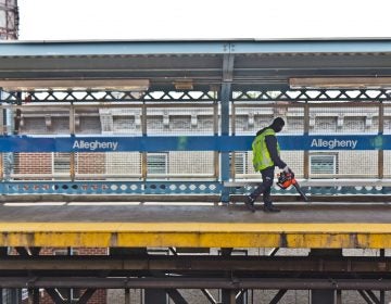 File photo: A worker uses a leaf blower to move trash onto the tracks at Allegheny SEPTA station. (Kimberly Paynter/WHYY)