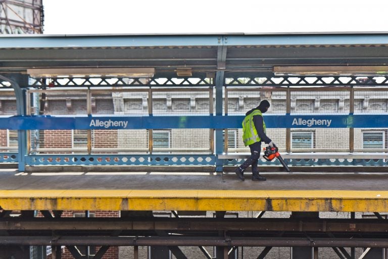 File photo: A worker uses a leaf blower to move trash onto the tracks at Allegheny SEPTA station. (Kimberly Paynter/WHYY)