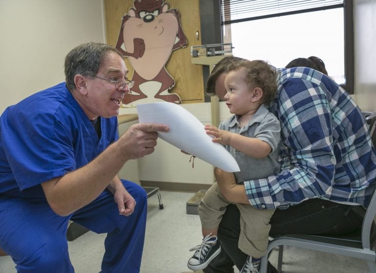 Pediatrician Charles Goodman, left, talks to Frank Fierro, the father of 1 year-old Cameron Fierro. (AP Photo/Damian Dovarganes)