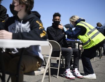 East Hartford High School junior Zander Robinson receives a vaccination from EMT Mary Kate Staunton of Clinton at a mass vaccination site at Pratt & Whitney Runway in East Hartford, Conn., Monday, April 26, 2021. Community Health Center, Inc. (CHC) hosted a 