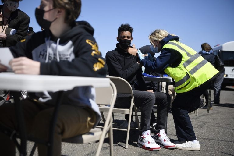 East Hartford High School junior Zander Robinson receives a vaccination from EMT Mary Kate Staunton of Clinton at a mass vaccination site at Pratt & Whitney Runway in East Hartford, Conn., Monday, April 26, 2021. Community Health Center, Inc. (CHC) hosted a 