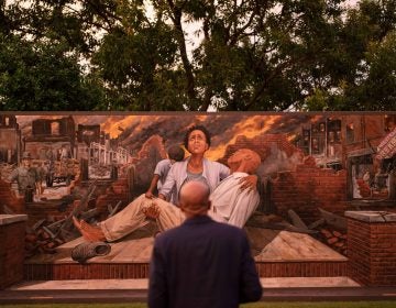 In this Thursday, May 27, 2021 file photo, Darius Kirk looks at a mural depicting the Tulsa Race Massacre in the historic Greenwood neighborhood ahead of centennial commemorations of the massacre in Tulsa, Okla. (AP Photo/John Locher)