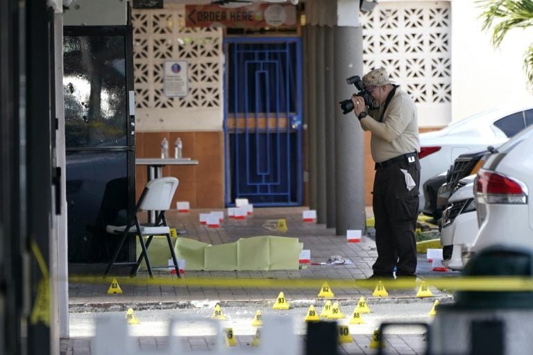 Police take photos at the scene of a shooting outside a banquet hall, with evidence markers seen on the ground