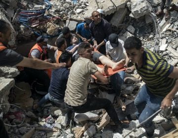 Palestinian rescuers carry a survivor man from under the rubble of a destroyed residential building following Israeli airstrikes