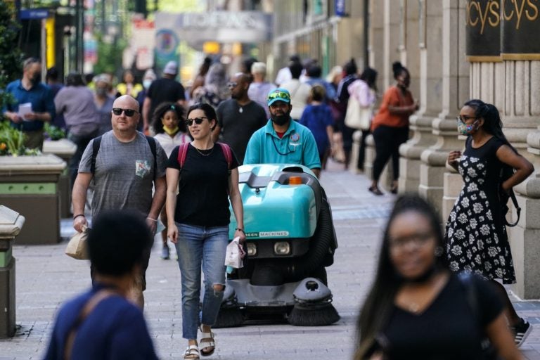 People, some without masks, walk along Market Street